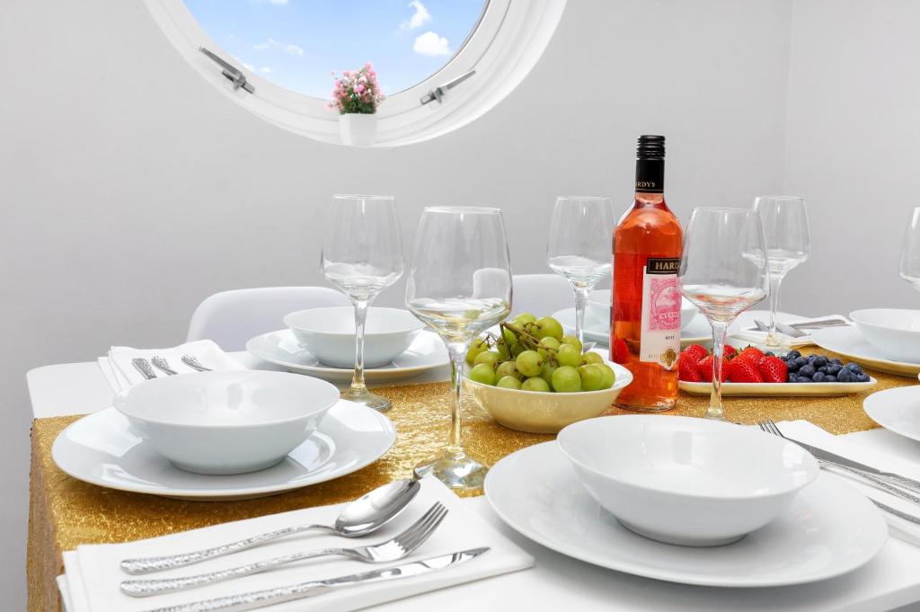 einen Tisch mit Tellern und Gläsern sowie eine Flasche Wein in der Unterkunft Waterside 4 Bed Apartment in London