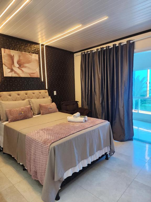 a bedroom with a bed and a large window at Flats Bahia in Coruripe