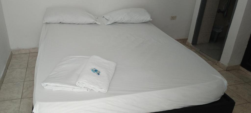 ein weißes Bett mit weißer Bettwäsche und einem Handtuch darauf in der Unterkunft Hotel Río Mar in Cartagena de Indias