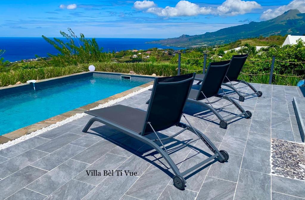 um grupo de cadeiras sentadas ao lado de uma piscina em Villa Bèl Ti Vue Piscine Vue Mer et Montagne Pelée em Le Carbet