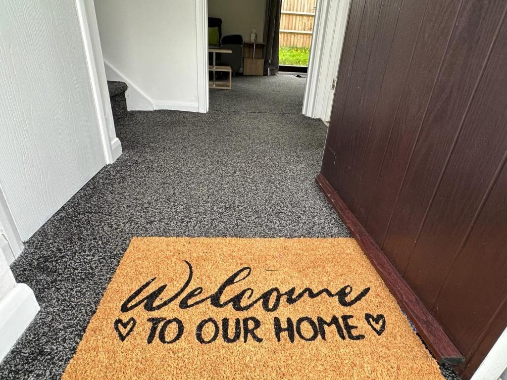 a welcome to our home sign on a door mat at Homely Milton Keynes Stay! in Milton Keynes