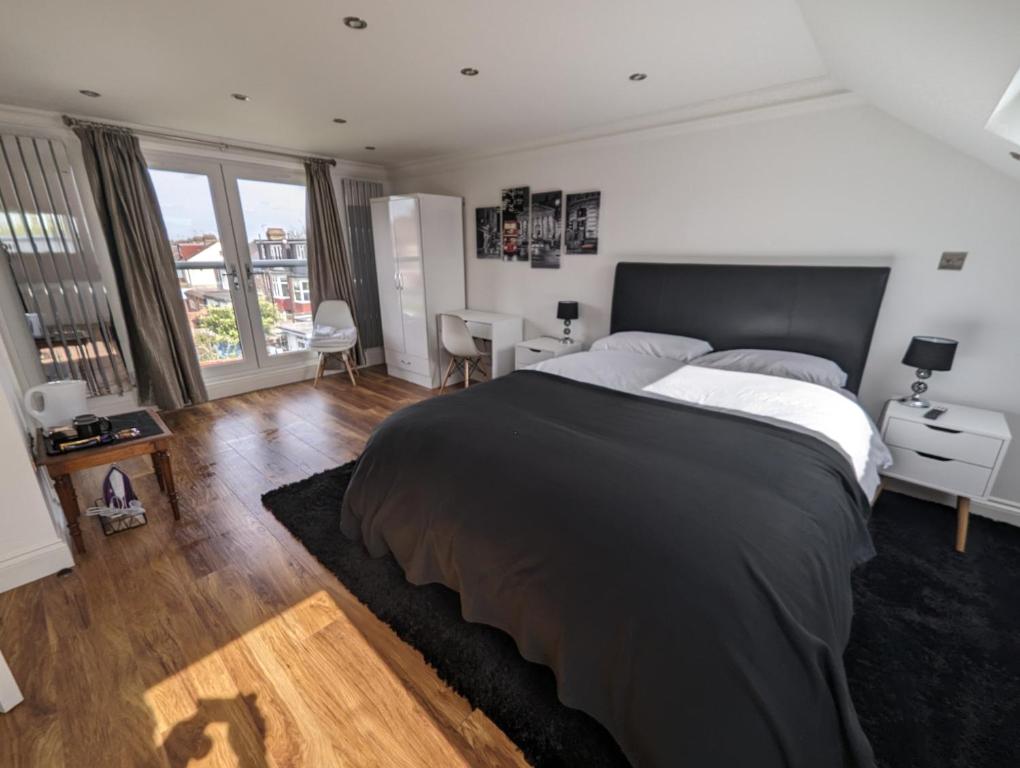 a bedroom with a large bed and a desk at Luxury Hotel Rooms in Palmers Green