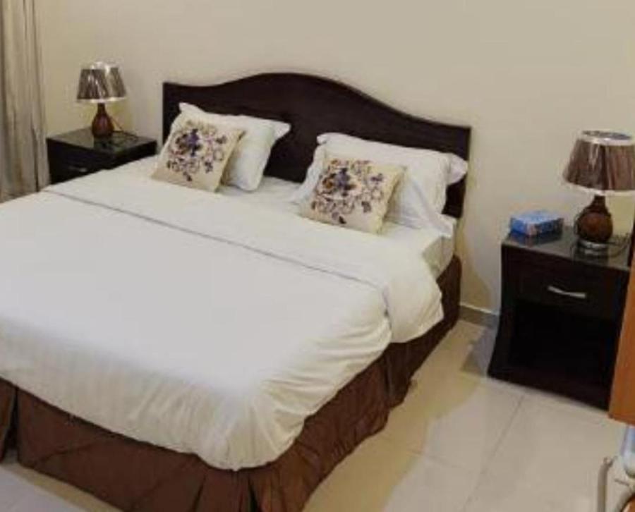 a bedroom with a large bed with white sheets and pillows at جراند روزالينا جازان in Bakhshat Yamanī