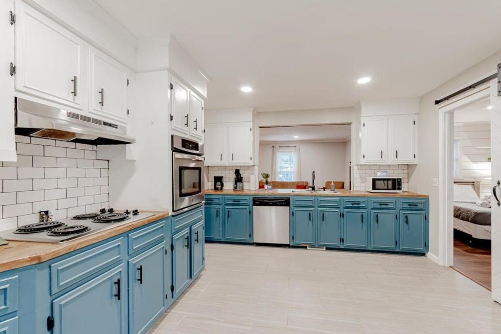 a large kitchen with blue cabinets and white walls at Settle Inn-- 10mi to Columbia, Mins to Lake Murray in Irmo