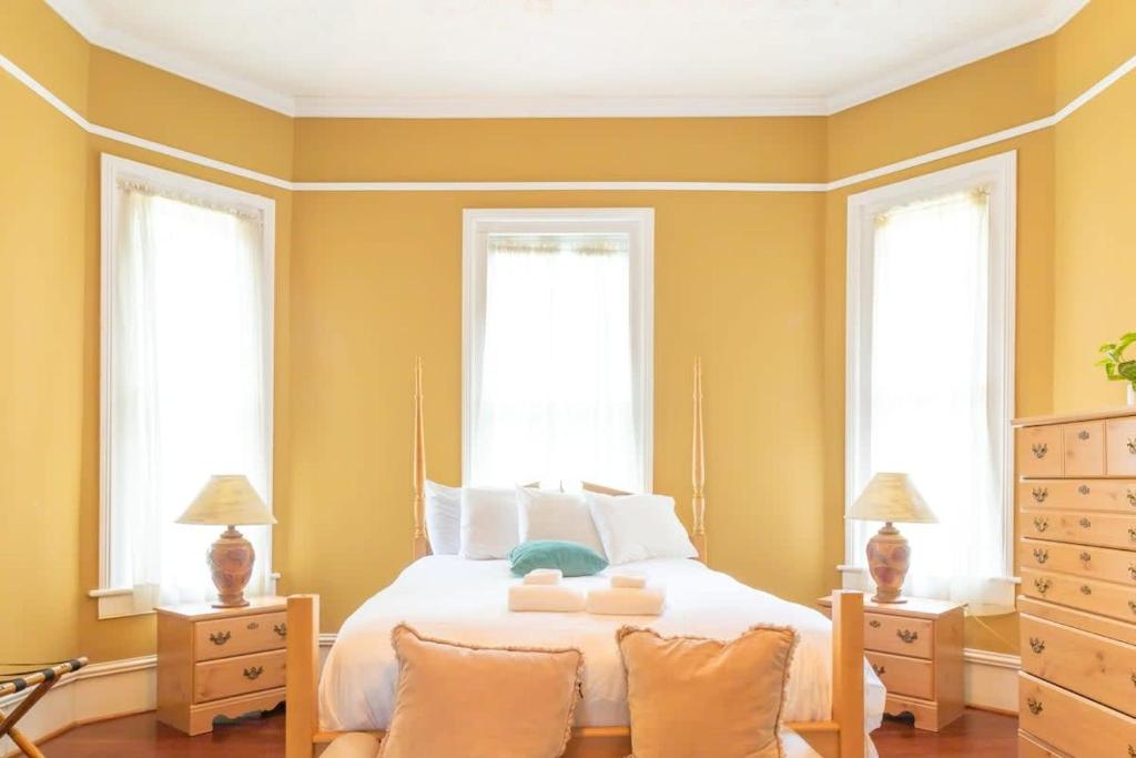 een slaapkamer met een bed en 2 ramen bij Goldfinch Mansion Historic Luxury on the Park in Columbus