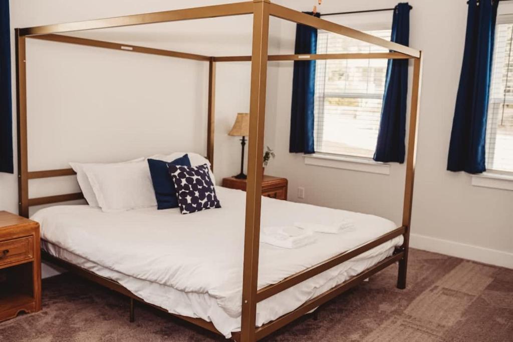 a bedroom with a four poster bed with blue curtains at The Capital Cottage New Home Near USC & Bases in Columbia