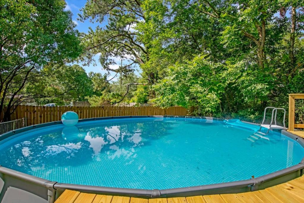 a large swimming pool with a wooden deck and a wooden fence at Midcentury Modern - Pool & Hot tub - Retro Retreat in Mobile