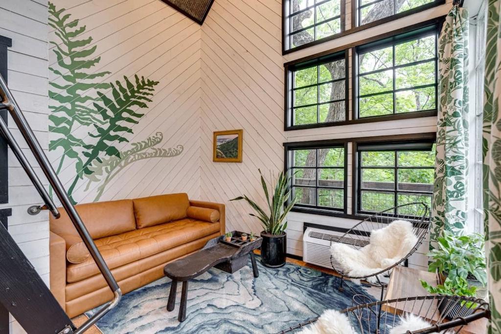 sala de estar con sofá y algunas ventanas en Treetop Hideaways: The Wood Lily Treehouse en Chattanooga
