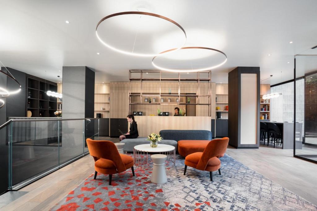 a lobby with a table and chairs and a person at Crowne Plaza Geneva, an IHG Hotel in Geneva