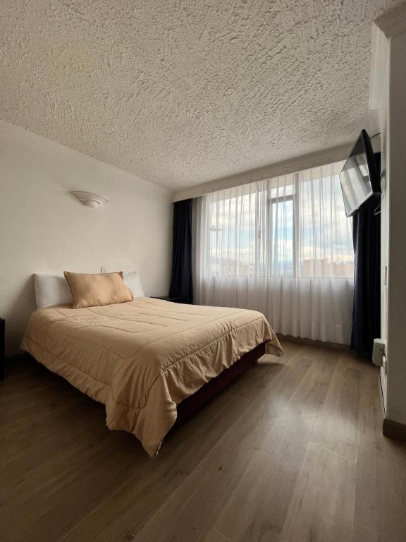 1 dormitorio con cama y ventana grande en Hotel Paipa Real en Paipa