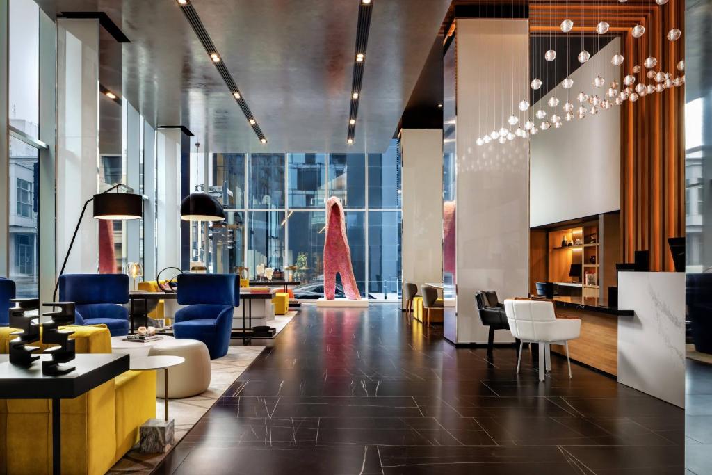 a lobby with chairs and tables in a building at Humaniti Hotel Montreal, Autograph Collection in Montréal