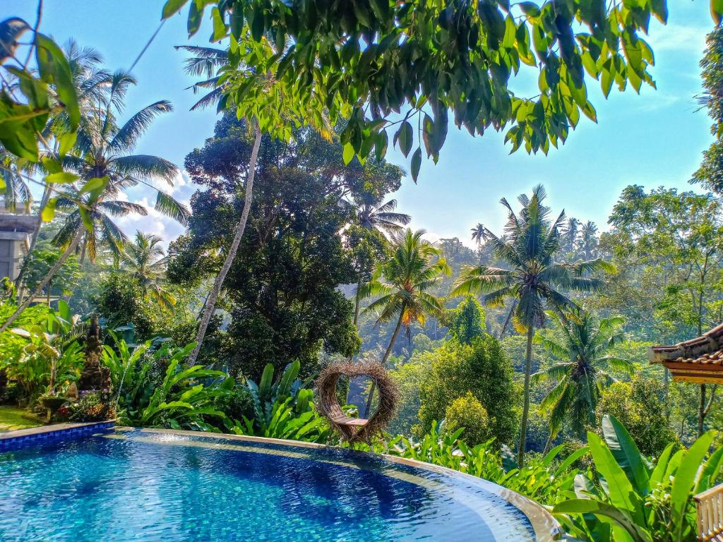 a swimming pool in the middle of a tropical garden with trees at Made Punias Jungle Paradise in Ubud