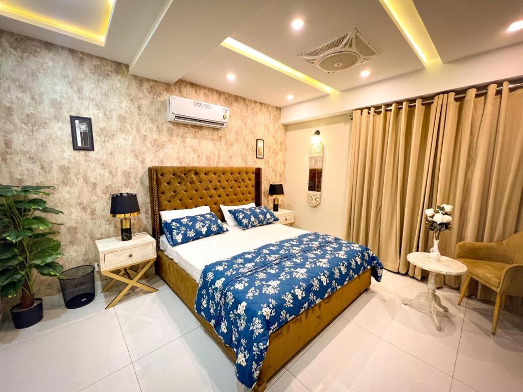 um quarto com uma cama com lençóis azuis e brancos em Bahria Town Lahore Prestige Apartments by LMY em Lahore