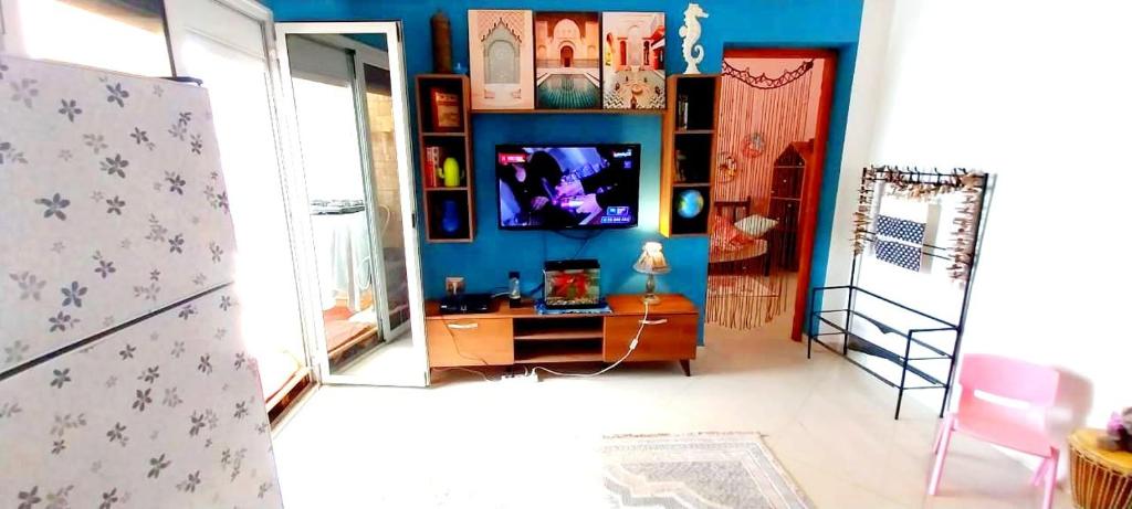 a living room with a tv and a blue wall at Chez trina house in Bizerte