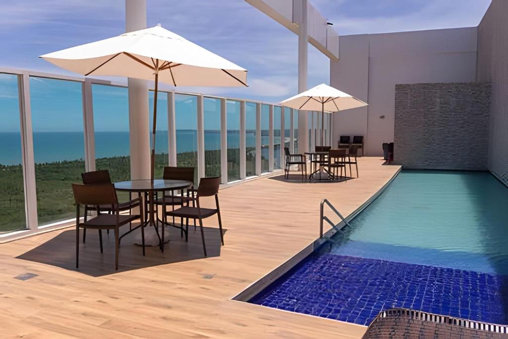 a balcony with tables and chairs and a swimming pool at Hosts BR - Flats Frente Mar c/ Cozinha in Recife