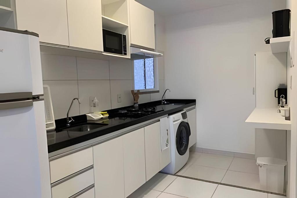 - une cuisine blanche avec un évier et un lave-linge dans l'établissement Hosts BR - Apartamentos funcionais, à Fortaleza
