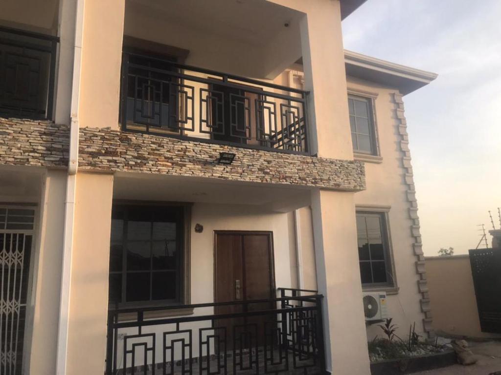 Biały dom z balkonem z czarną poręczą w obiekcie Serengeti Rest Lodge w mieście Afienya