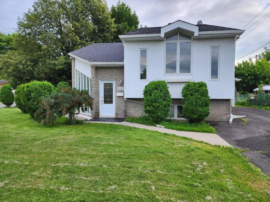 a white house with a green yard at Timeless Tranquility, a place near everything! in Longueuil