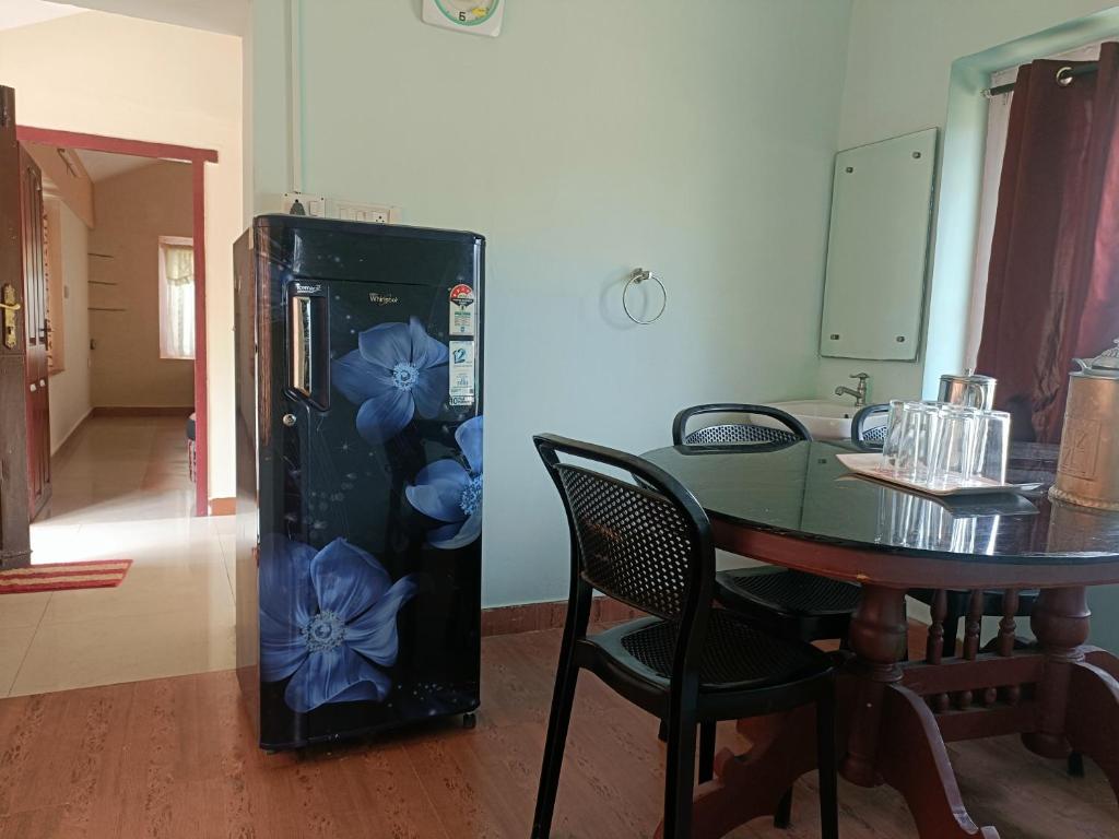 Un refrigerador negro con flores azules junto a una mesa. en QUEENS COTTAGE - individual cottage en Ooty