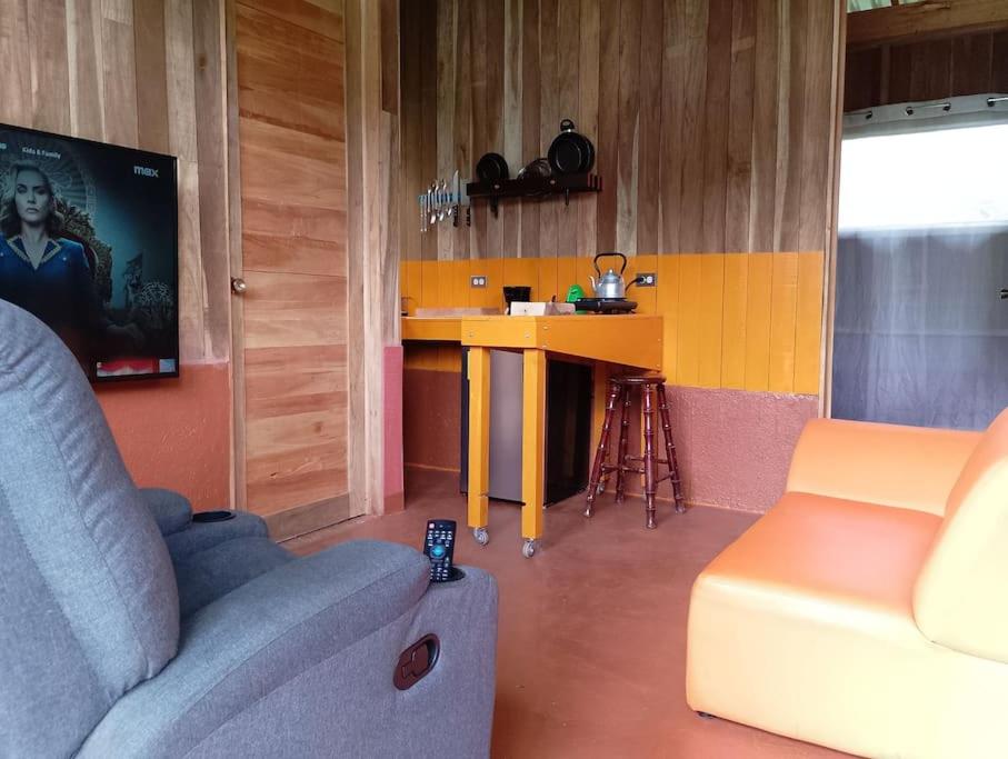 een woonkamer met een bank en een tafel met een tv bij Cabina Gooder in Chachagua