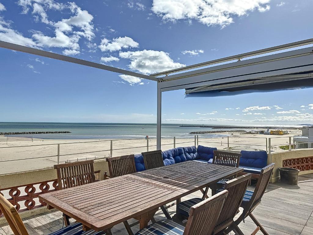 - une table et des chaises en bois sur une terrasse donnant sur la plage dans l'établissement Appartement F4 Carnon avec terrasse, parking, climatisation, wifi, accès plage - FR-1-715-92, à Mauguio