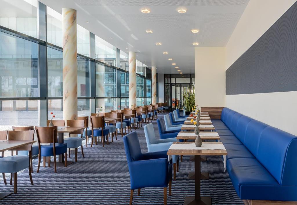 a restaurant with blue chairs and tables and windows at Holiday Inn Express Singen, an IHG Hotel in Singen