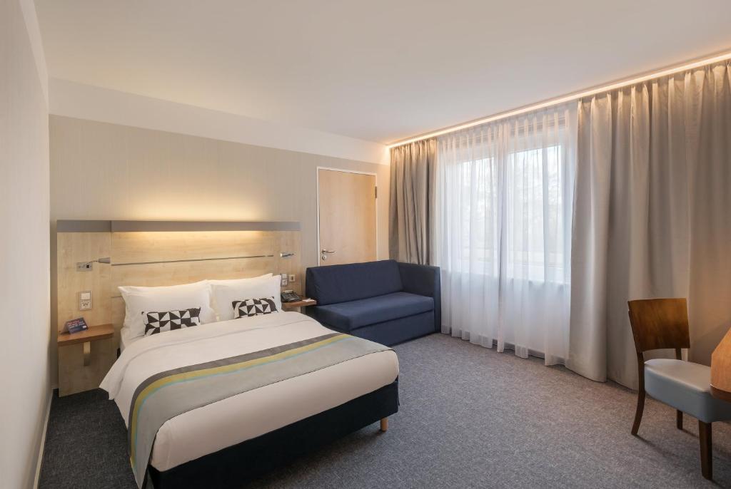 a hotel room with a bed and a blue chair at Holiday Inn Express Singen, an IHG Hotel in Singen