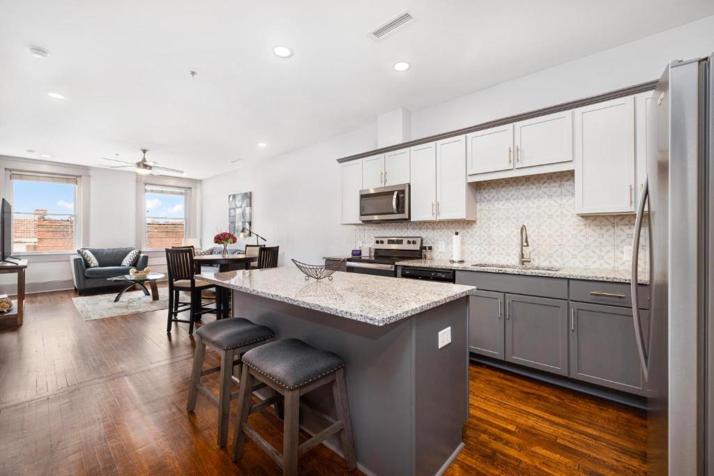 a kitchen with white cabinets and a kitchen island with bar stools at Brand new luxury 2BR loft in downtown Johnson City in Johnson City