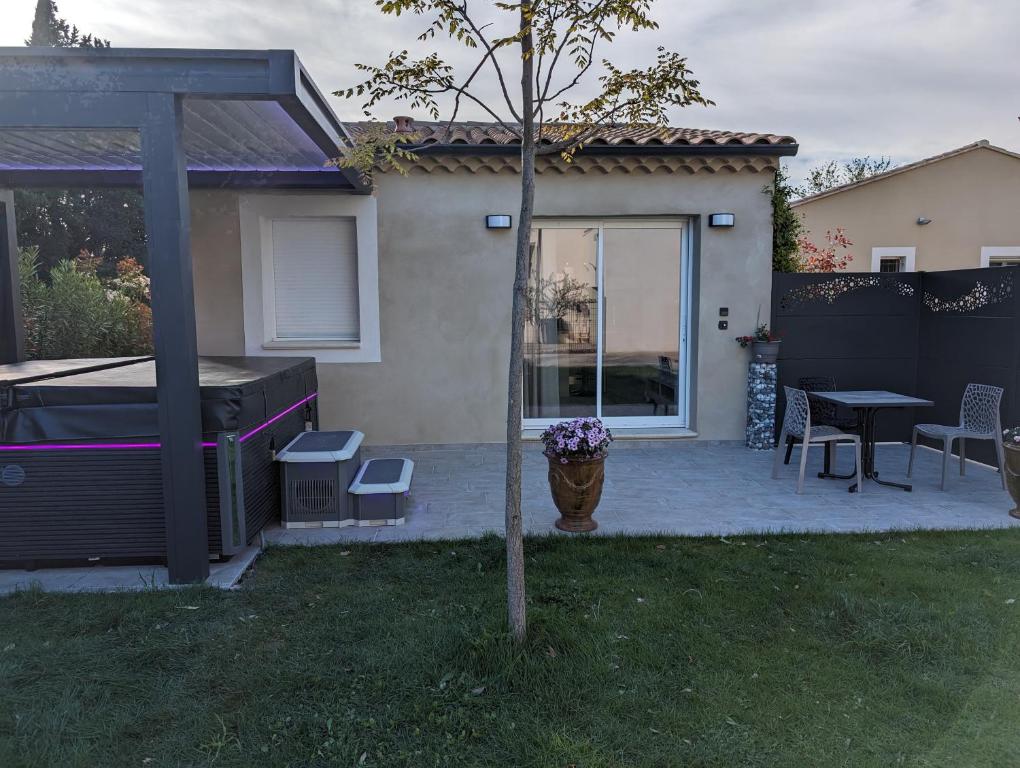 ein Haus mit einer Terrasse mit einem Tisch und einem Zaun in der Unterkunft Hébergement de vacances Chez Patrick et Patricia in Aubignan