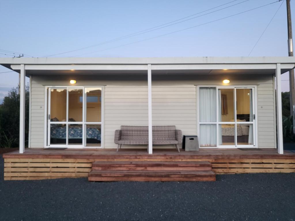 a house with a bench on a wooden deck at TradeStop Short-Term Accomodation in Raglan