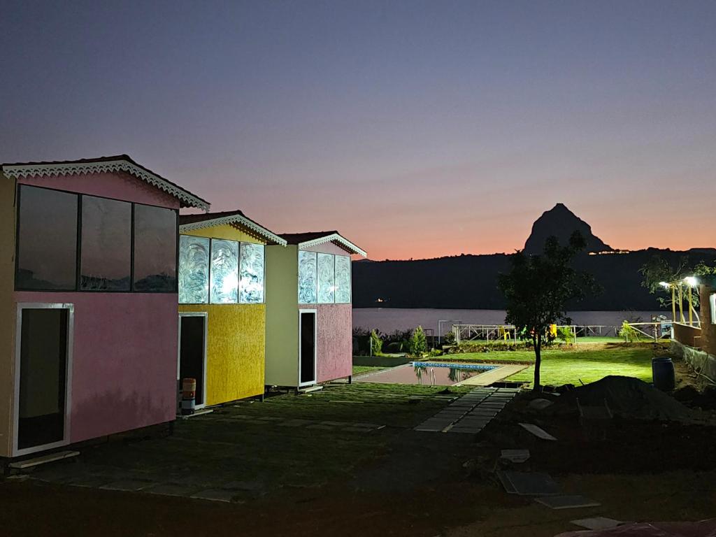 a building with a sunset in the background at Plumeria Retreat pawna lakeside cottages in Malavli