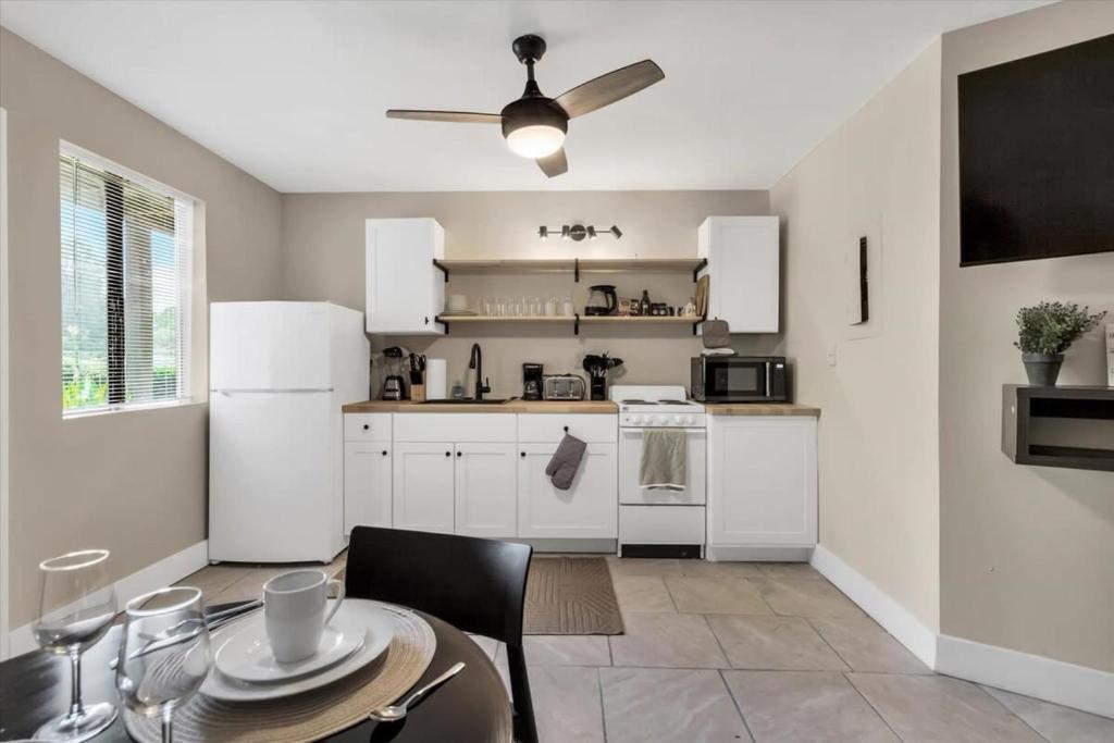 a kitchen with white cabinets and a table and a ceiling fan at King Bed Modern Studio Apartment in Huntsville