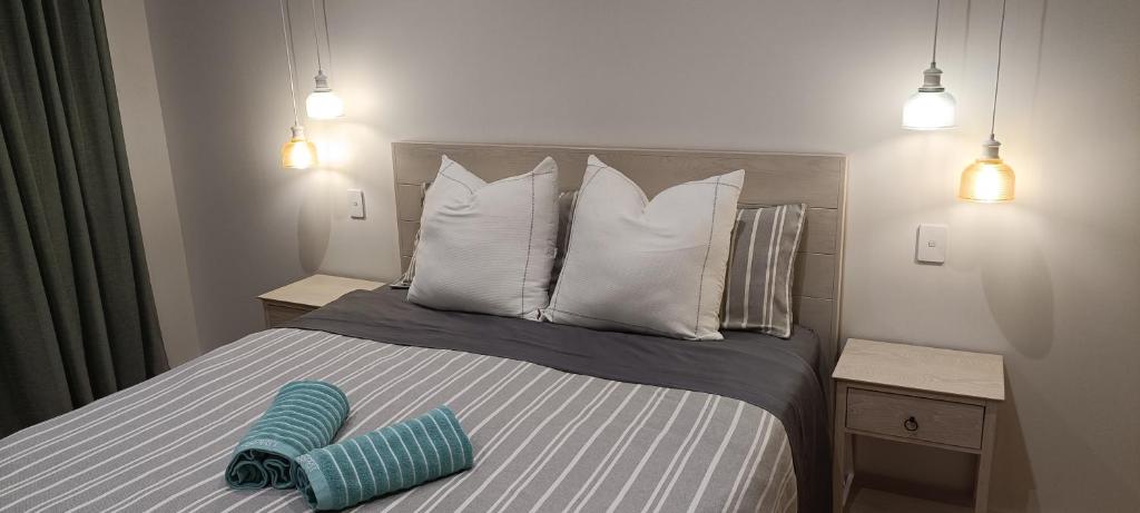 ein Bett mit weißen Kissen und einem blauen Objekt darauf in der Unterkunft Luxurious waterfront accommodation in Dunedin