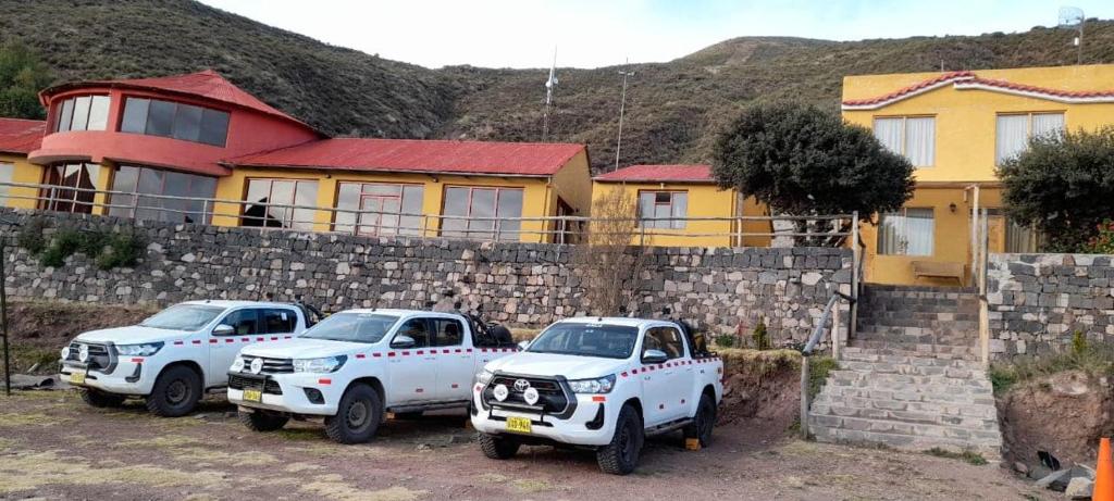 two white trucks parked in front of a stone wall at Hotel Mirador del Colca Lodge in Chivay