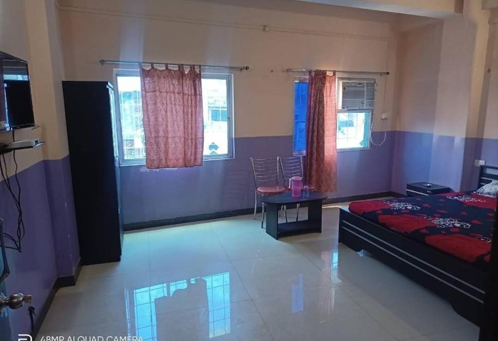 1 dormitorio con cama, mesa y ventanas en Hotel M.K. Palace en Gaya