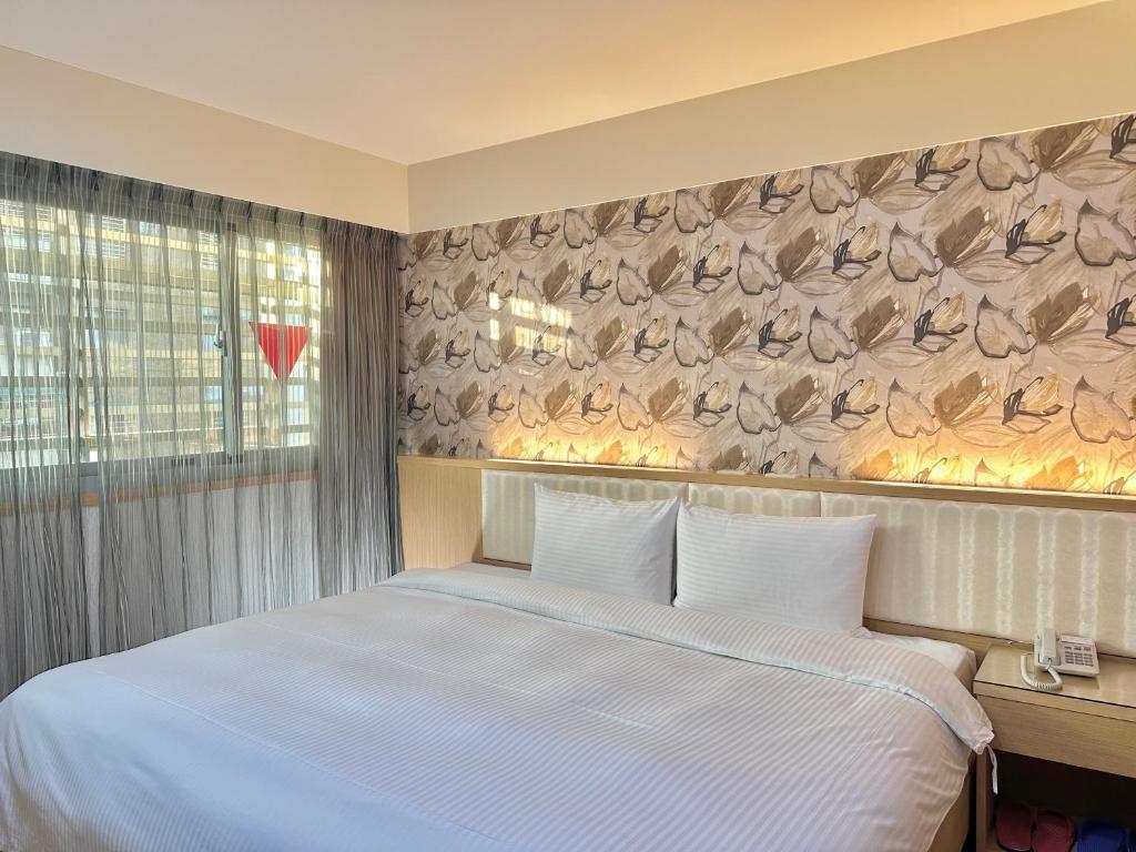 Un dormitorio con una cama blanca y una pared con plumas en Mei Hotel, en Taichung