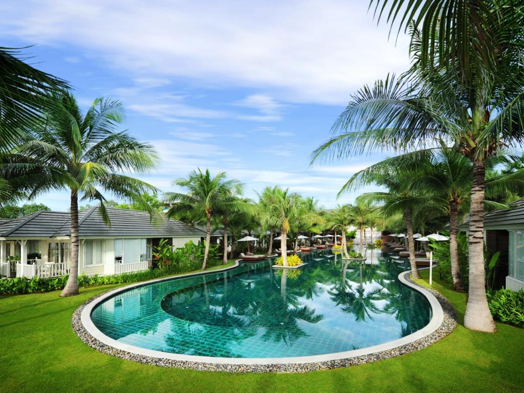 a swimming pool in a yard with palm trees at Rest Detail Hotel Hua Hin in Hua Hin