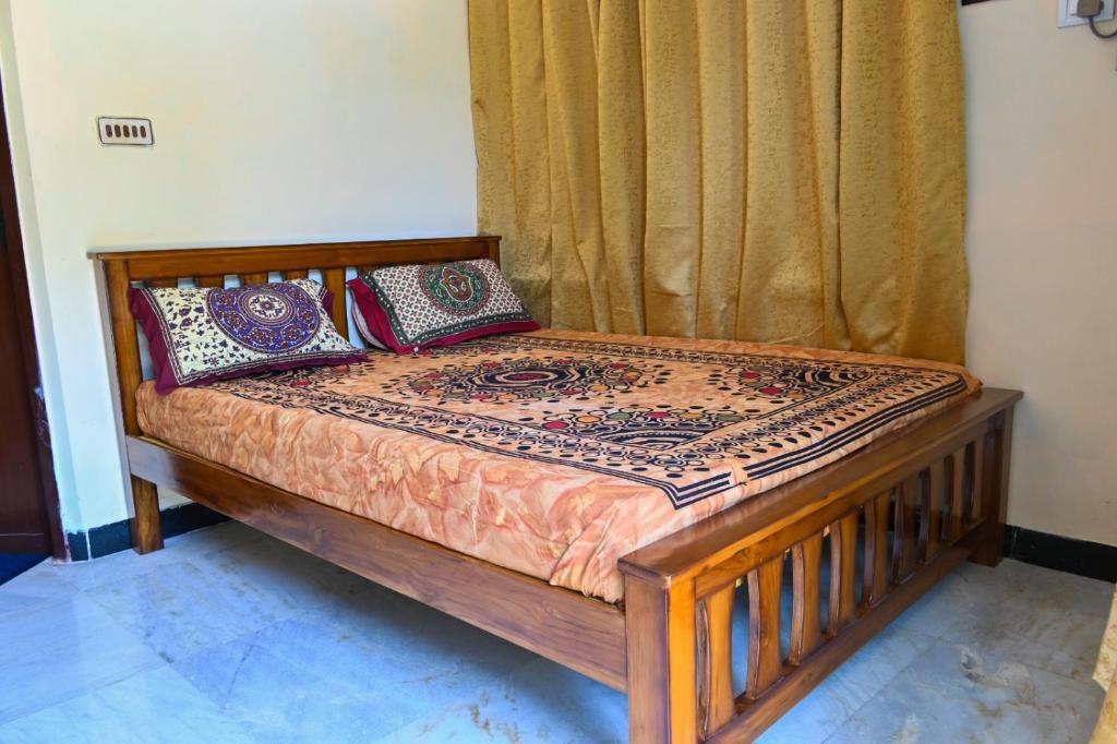 a wooden bed with pillows on it in a room at Panaiyur Guest house in Chennai