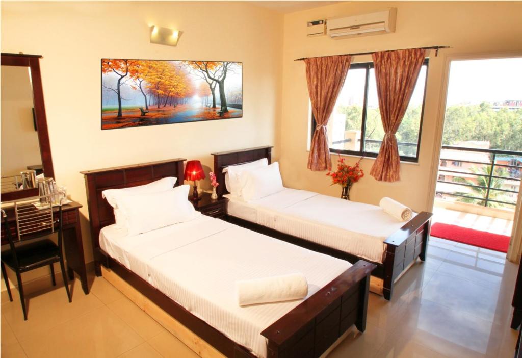 バンガロールにあるBROOKKEFIELD CORPORATE HOMESのベッド2台、デスク、窓が備わる客室です。