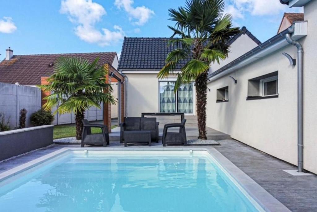 a swimming pool in the backyard of a house with palm trees at Chambre chez l'habitant avec piscine 400m Circuit 24h Le Mans in Le Mans