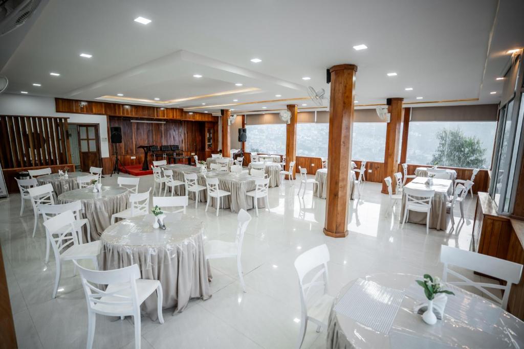 einen Bankettsaal mit weißen Tischen und weißen Stühlen in der Unterkunft 2K HOTEL in Kohīma