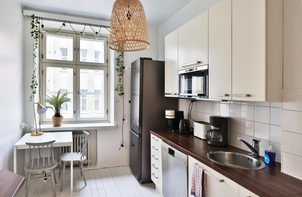 a kitchen with a sink and a refrigerator at Design stay in the heart of Punavuori in Helsinki