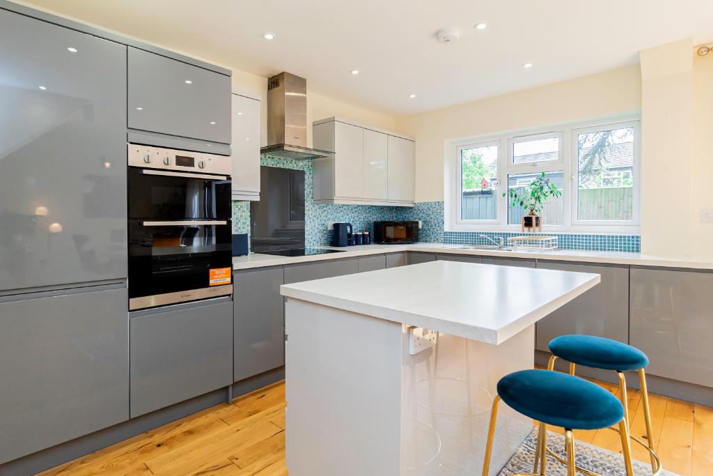 una cocina con encimera blanca y taburetes azules en Relaxing 4 Bedroom Retreat For Long Stays Fawley, en Totton