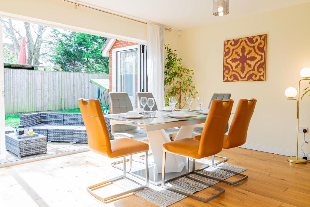 a dining room with a white table and orange chairs at Relaxing 4 Bedroom Retreat For Long Stays Fawley in Totton