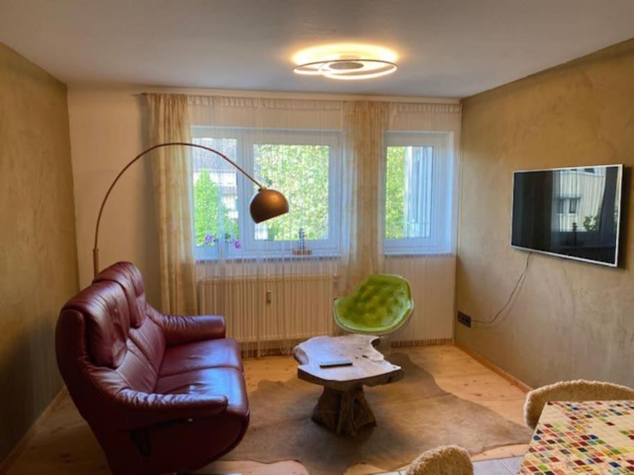 sala de estar con sofá de cuero y silla verde en City Apartment Markdorf, en Markdorf