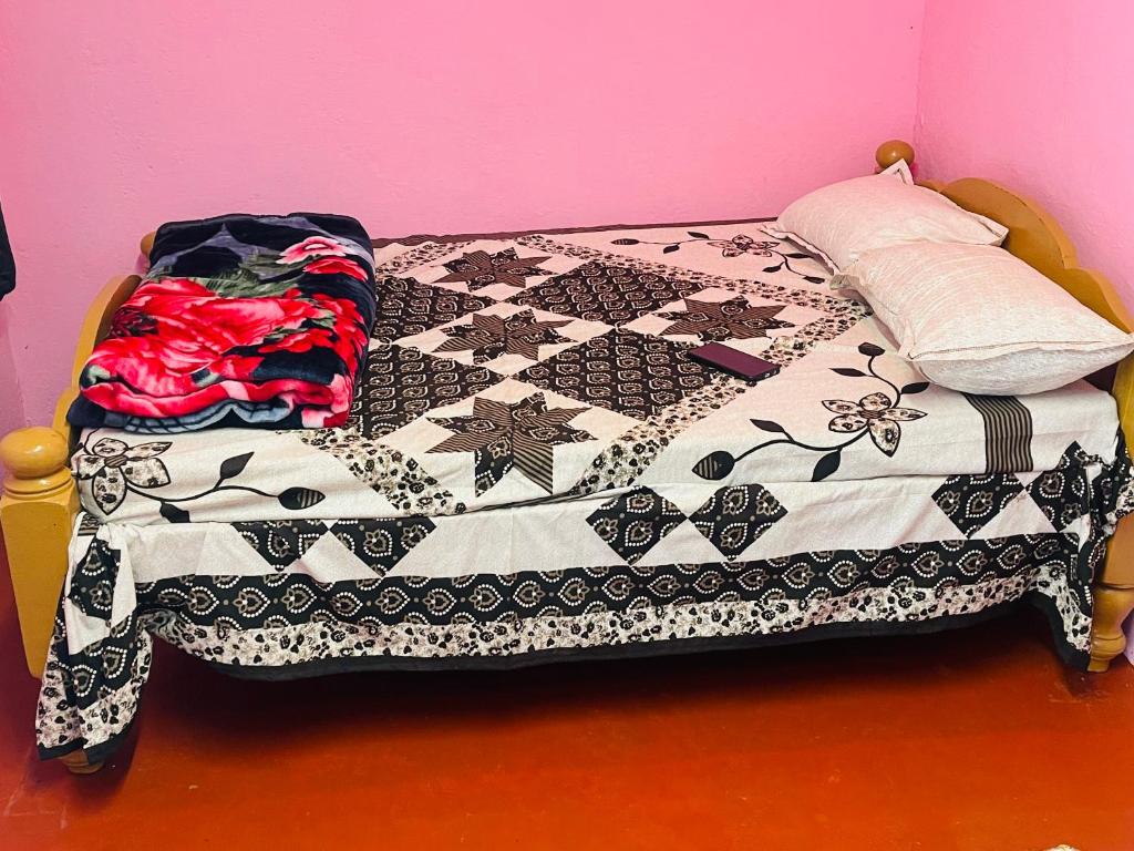 a bed with a black and white quilt on it at Coorg Green Moon in Madikeri
