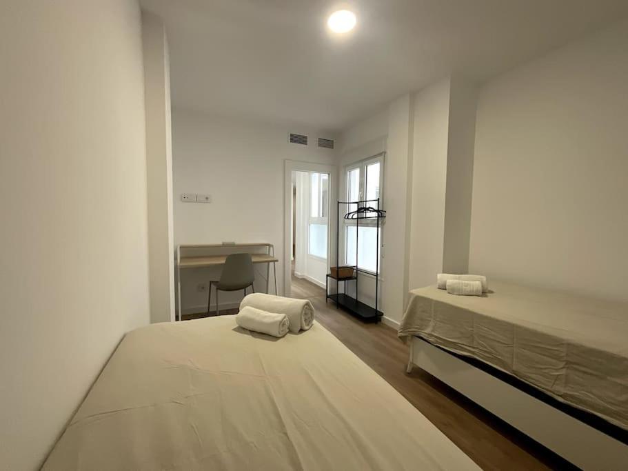a white bedroom with a large bed and a desk at Piso nuevo Almeria Centro in Almería