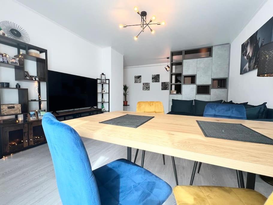 a dining room with a large wooden table and blue chairs at Central, spacius apartment. in Bucharest