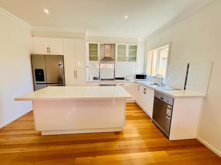 a large kitchen with white cabinets and a wooden floor at Townhouse Near The World’s Coolest High st in 2024 in Melbourne