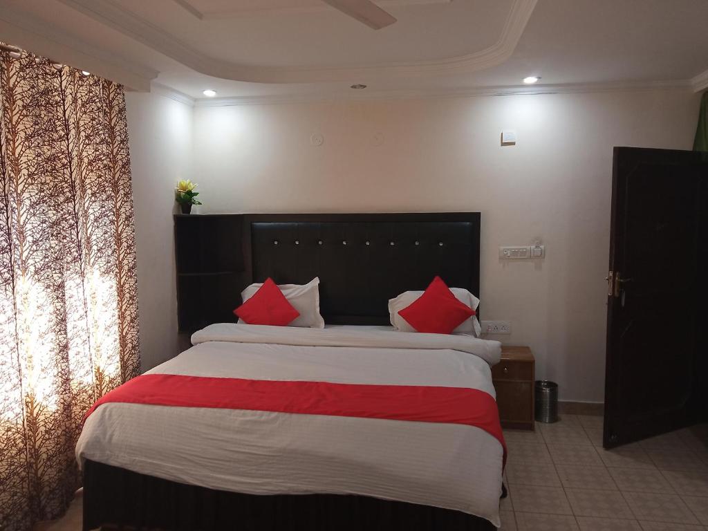Un dormitorio con una cama grande con almohadas rojas. en vella marina group of hotel Ravine, en Dharamshala